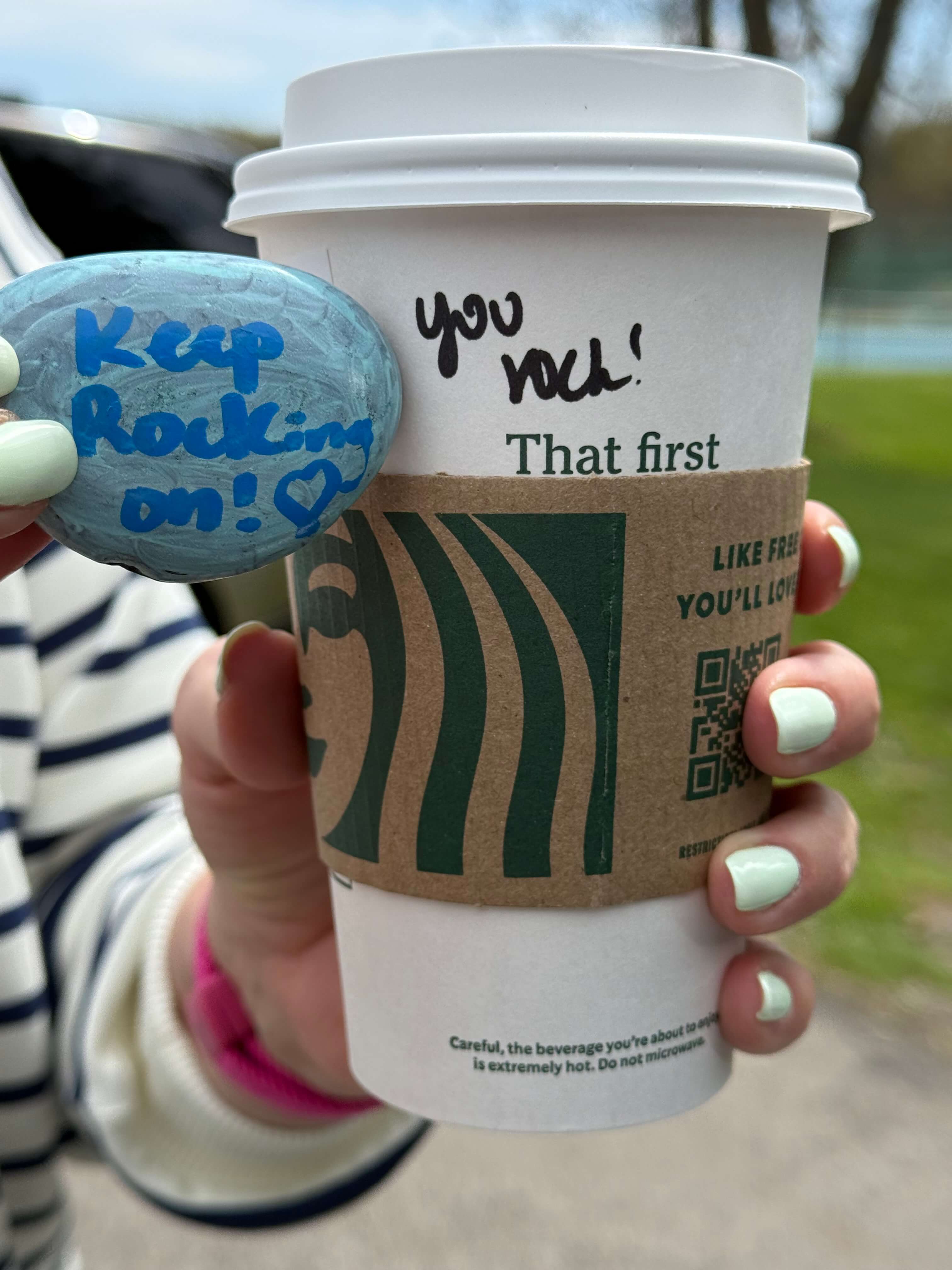 A painted rock and coffee cup displaying the same encouraging message