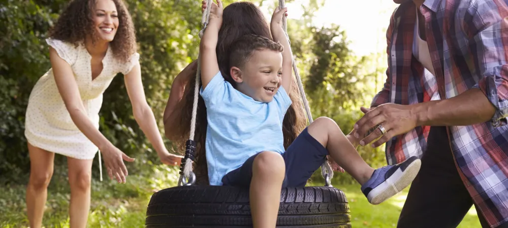 tire-swing Family of four playing on a tire swing together